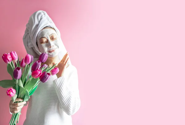 Funny asian woman with beauty mask and tulips on pink background. Happy international women day.