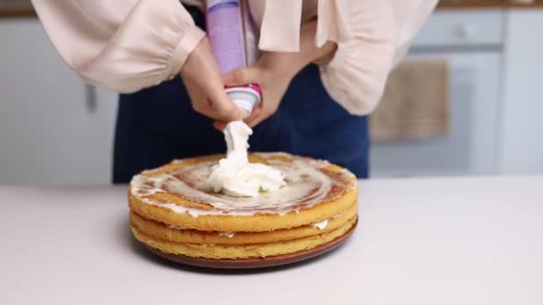 亚洲女人在厨房里的蛋糕上涂奶油 装卸工的女人在海绵蛋糕上倒奶油 做自制的蛋糕 烘焙的概念 奶油海绵蛋糕加奶油 — 图库视频影像