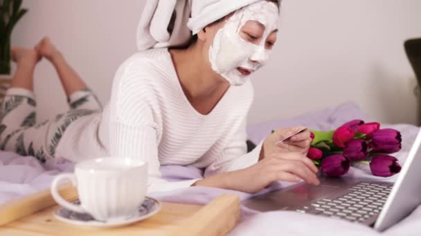 Kinesisk Kvinna Bär Ansiktsmask Njuter Hemma Och Använder Sin Bärbara — Stockvideo