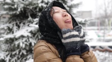 Komik Asyalı kız kışın ağzıyla kar taneleri yakalıyor. Açık havada güzel bir kızın portresi.