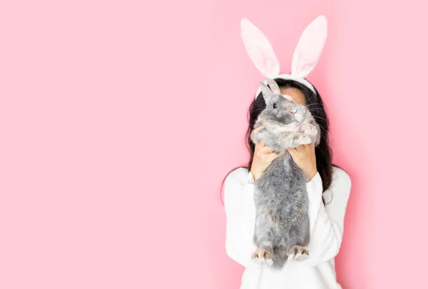 滑稽快乐的女孩 长着小兔子耳朵 带着灰兔子粉红的背景 — 图库照片