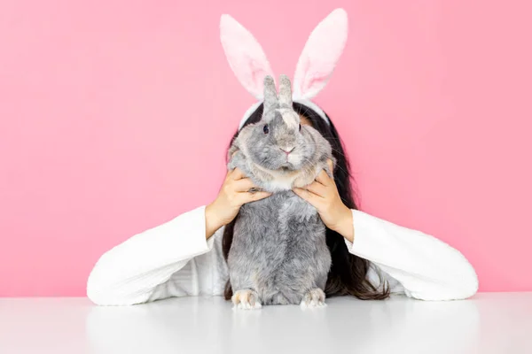 滑稽快乐的女孩 长着小兔子耳朵 带着灰兔子粉红的背景 — 图库照片