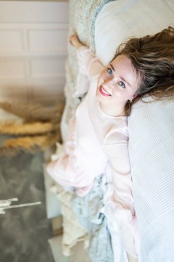 Gülücükler saçan genç bir kız, modern bir evde sabah yatağında dinleniyor..