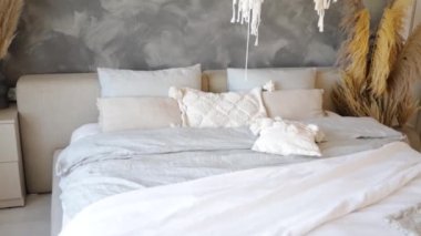 Beyaz yatak odasının içinde kuru çiçekler, moda çatı katı tasarımı ve çift kişilik yataklı beyaz çarşaflar var.