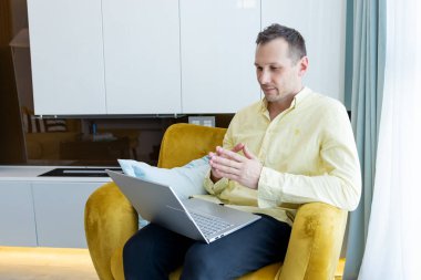 Ev ofisindeki koltuğa yaslanmış dizüstü bilgisayar kullanan serbest çalışan ciddi bir milenyum öğrencisiymiş. İşadamı dairede uzaktan not defteri üzerinde çalışıyormuş.