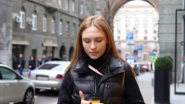 Yüzü kızıl saçlı genç kadın kameraya bak. Gülümse. Sokaklarda dur.