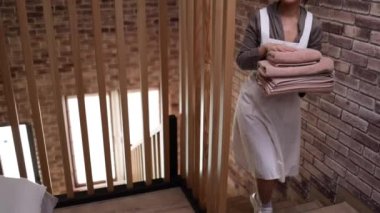 Asyalı kadın hizmetçi otel odasındaki yatağa temiz havlu koyar.