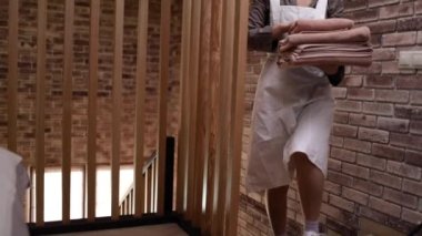 Asyalı kadın hizmetçi otel odasındaki yatağa temiz havlu koyar.