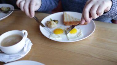 Geleneksel İngiliz kahvaltısı. Adam sahanda yumurta keser ve restoranda yumurta sarısına ekmek batırır..