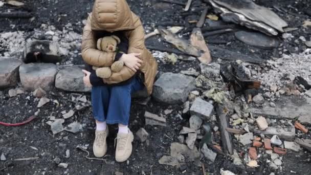 戦争で破壊された家の隣の女の子 ウクライナでの戦争 ウクライナ難民 戦争で破壊された彼の家の廃墟の子供 平和の概念 — ストック動画