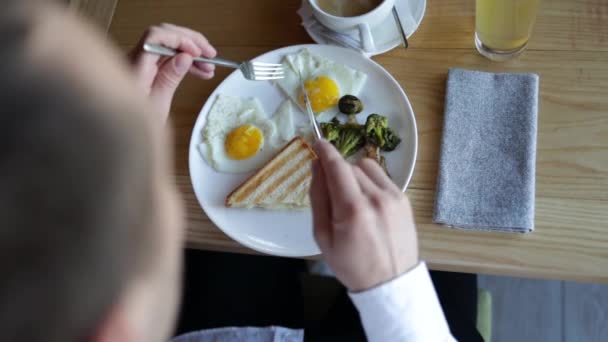 传统的全英式早餐特写 男人在餐馆切煎蛋 在蛋黄中蘸面包 — 图库视频影像