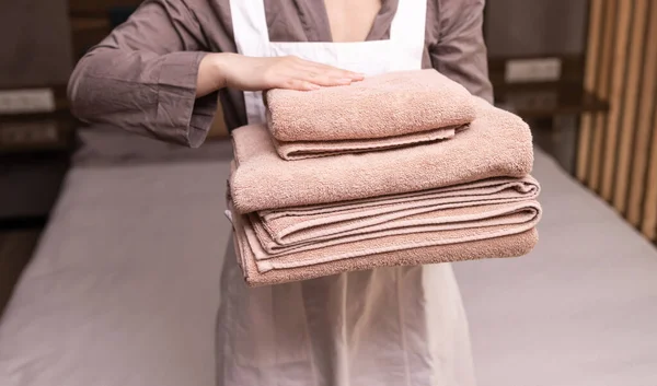 ホテルの部屋に新鮮なタオルを積んだ女性メイド — ストック写真