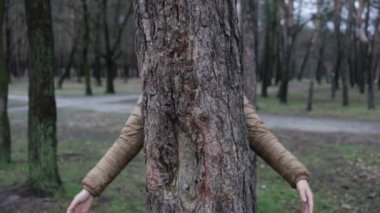 Ormanda ağaç gövdesine sarılan doğa aşığı. İnsanların kavramı doğayı sever ve ormansızlaşmadan, kirlilikten veya iklim değişikliğinden korur.