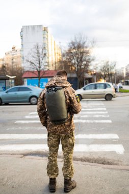 Ukraynalı asker bayrak ve mızrak tasvir eden sembolle askeri üniforma giyiyor. Şehir caddesinde askeri üniformalı bir adam var.. 