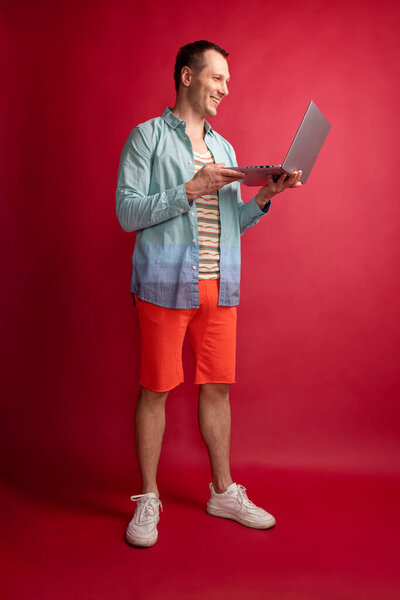 Фото красивой брюнетки парень типа ноутбук носить очки джинсы рубашку изолированы на красном фоне цвета