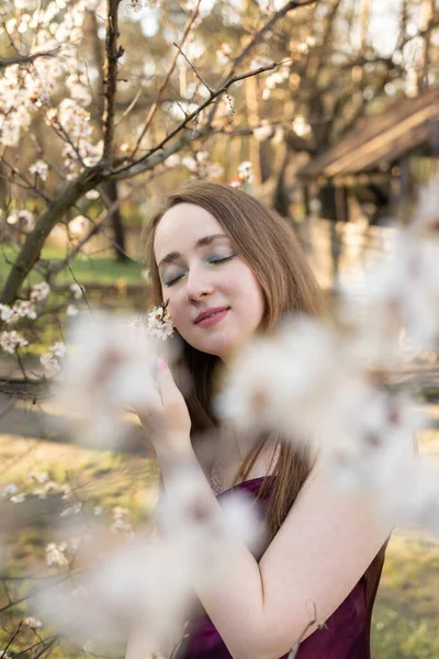 Pretty woman in cherry blossom garden, spring time