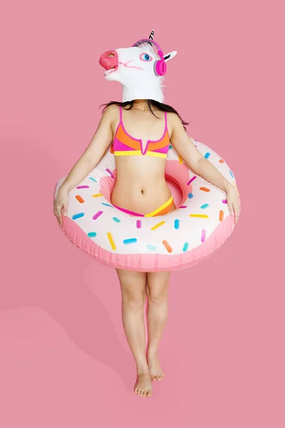快乐快乐的女人 身材苗条 身穿泳衣 独角兽头戴粉色充气环 背景是粉色的 暑期酒店游泳池休息的概念 — 图库照片