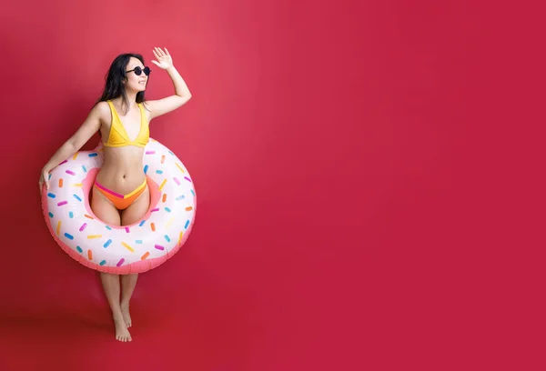 全长快乐的年轻性感亚洲女人身材苗条的泳衣摆设充气橡胶圈隔离在粉红的色彩墙背景工作室 夏日酒店游泳池海景日光浴概念 — 图库照片
