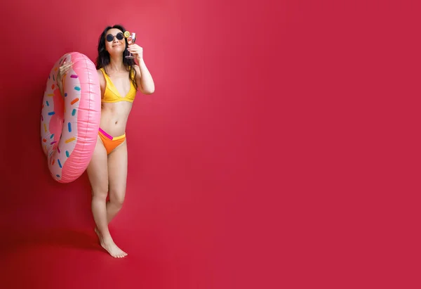 全长快乐的年轻性感亚洲女人身材苗条的泳衣摆设充气橡胶圈隔离在粉红的色彩墙背景工作室 夏日酒店游泳池海景日光浴概念 — 图库照片