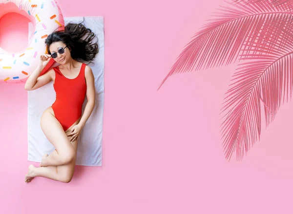 年轻性感的亚洲女人身材苗条 戴着红色泳衣太阳镜 躺在充气环状酒店游泳池上 隔离在粉红的背景下 暑假海上休息日光浴的概念 — 图库照片