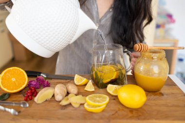 Tahta masada limon ve bal eşliğinde sağlıklı zencefil çayı yapmak.