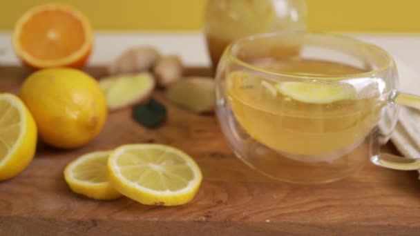 木のテーブルの上でレモンと蜂蜜と健康的な生姜茶を作るクローズアップ — ストック動画