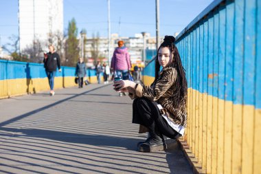 Ukrayna 'da Kyiv sokaklarında yürü. Köprüde oturan üzgün kadının portresi. Kahveyi başka tarafa bakıyor. Ukrayna 'da savaş yok. Ukraynalılara barış ve özgürlük. 