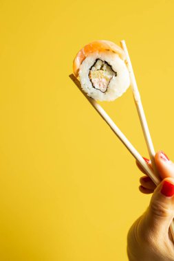 Somonlu suşi, karides ve sarı arka planda avokado..