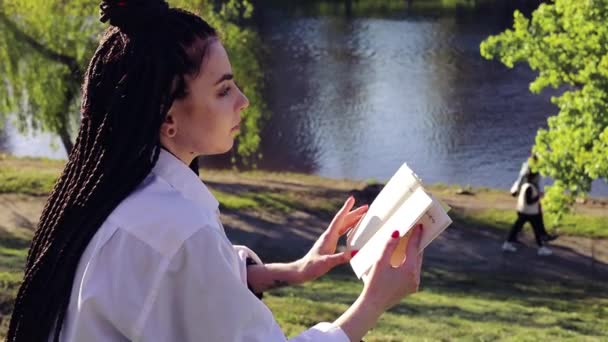 Νεαρή Γυναίκα Dreadlocks Διαβάζει Βιβλίο Στο Πάρκο Άνοιξη — Αρχείο Βίντεο