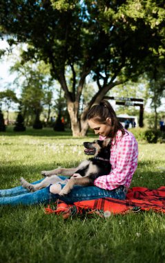 Güzel genç bir kadın, küçük kahverengi köpeğiyle dışarıda oynuyor. Öpücükler ve sarılmalar. Köpek dostu kavram. Yaşam biçimi.