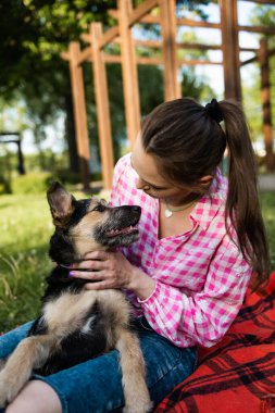 Güzel genç bir kadın, küçük kahverengi köpeğiyle dışarıda oynuyor. Öpücükler ve sarılmalar. Köpek dostu kavram. Yaşam biçimi.