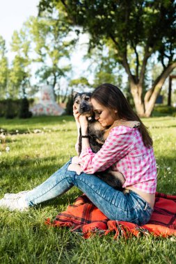 Güzel genç bir kadın, küçük kahverengi köpeğiyle dışarıda oynuyor. Öpücükler ve sarılmalar. Köpek dostu kavram. Yaşam biçimi.