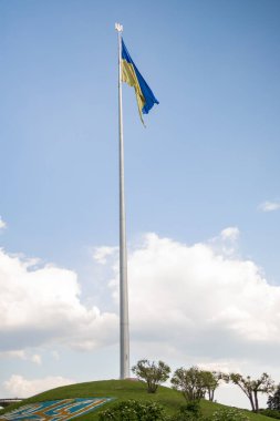Ukrayna bayrağı dalgalanırken mavi gökyüzünün altında, Ukrayna Anavatan 'ın ünlü heykelinin yanında.