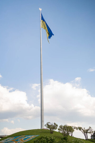 Ukrainian flag waving in the wind under blue sky, Ukraine near the famous statue of Motherland.