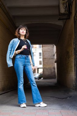 Güzel esmer kadın kot pantolon giyiyor ve Avrupa caddesinde yürüyor..