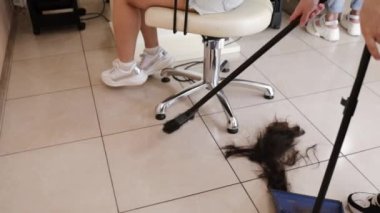 Hairdresser trimming brown hair with scissors. Woman cutting hair with barber scissors in beauty studio. Hair Stylist doing female haircut in hairdressing salon. Beauty and style concept.