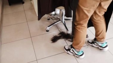 Hairdresser trimming brown hair with scissors. Woman cutting hair with barber scissors in beauty studio. Hair Stylist doing female haircut in hairdressing salon. Beauty and style concept.