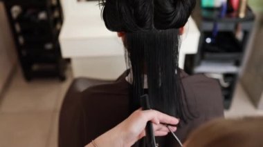 Hairdresser trimming brown hair with scissors. Woman cutting hair with barber scissors in beauty studio. Hair Stylist doing female haircut in hairdressing salon. Beauty and style concept.