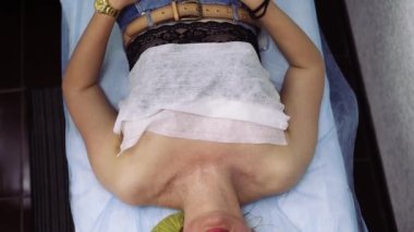 Genç orta yaşlı kadın hoş bir masaj yaptırırken rahatlıyor, terapist nazikçe yüz, omuz ve boyun masajı yapıyor..