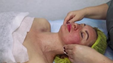 Terapist müşterilerin yüzünü temizlemek için sünger kullanır. Kozmetikçilerin kabinesinde güzellik ve spa prosedürleri, nazikçe yüz, omuz ve boyun masajı.