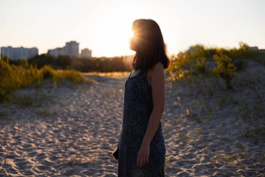 Tarlalarda gün batımına hayran genç bir kadının silueti.