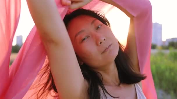 空と太陽のフレアの背景に風で舞う赤い布をなびかせながら 官能的なアジアの少女 優しさの概念 — ストック動画