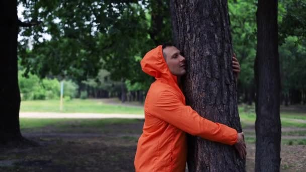 Jedność Naturą Młody Pozytywny Mężczyzna Pomarańczowy Płaszcz Ściskając Drzewo Lesie — Wideo stockowe