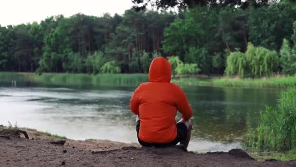 Junger Mann Sitzt Der Nähe Des Sees Und Blickt Auf — Stockvideo