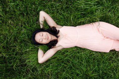 Genç bir Asyalı kadının portresi çimlerin üzerinde yatıyor, kopyalama alanı..