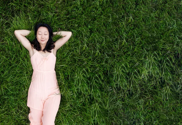 一个年轻的亚洲女人躺在草地上的画像 复制空间 — 图库照片