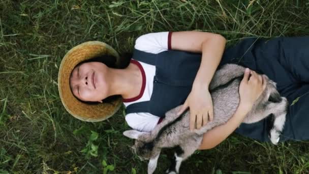 Genç Asyalı Kadın Yeşil Tarlada Oturan Sevimli Keçi Yavrusunu Tutuyor — Stok video