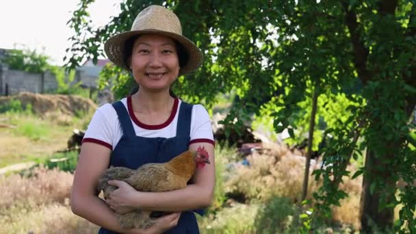笑顔幸せ 若いアジアの女性保持鶏彼女の手で彼女の農場 — ストック動画