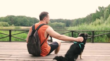 Şirin küçük köpek ve sahibi parkta birlikte oynuyorlar. Kürklü köpek okşamayı ve insanın en iyi arkadaşıyla iyi vakit geçirmeyi sever. Parktaki çimlerde eğleniyorum. Koşumlu köpek.