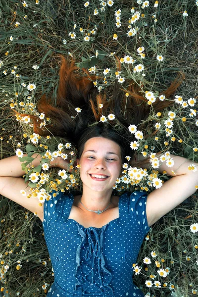 Sarışın güzel bir kadının papatya tarlasında yatarken fotoğrafı, papatya çayır kokusunun tadını çıkaran tatlı bir kadın, çiçek tarlasında rahatlamış, bahar doğasında eğlenen tatlı bir genç kız..